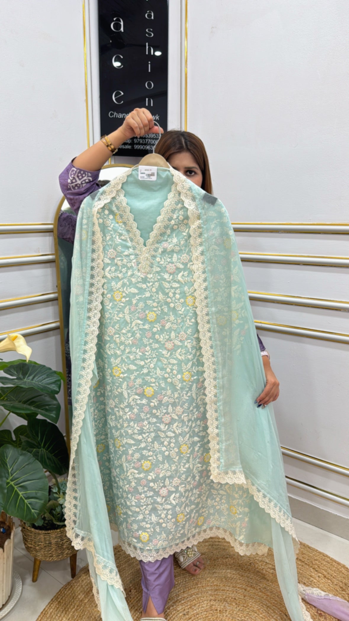 Kota Doria unstitched suit in light blue with intricate embroidery and lace detailing, displayed on a hanger