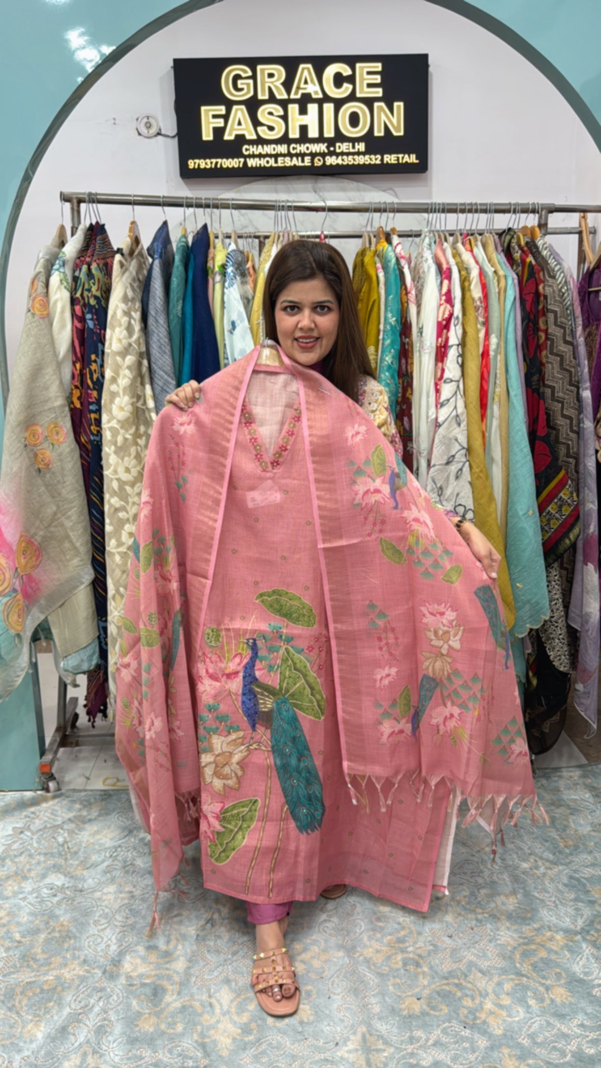 Woman showcasing a pink linen semi party wear suit with floral embroidery in a boutique setting