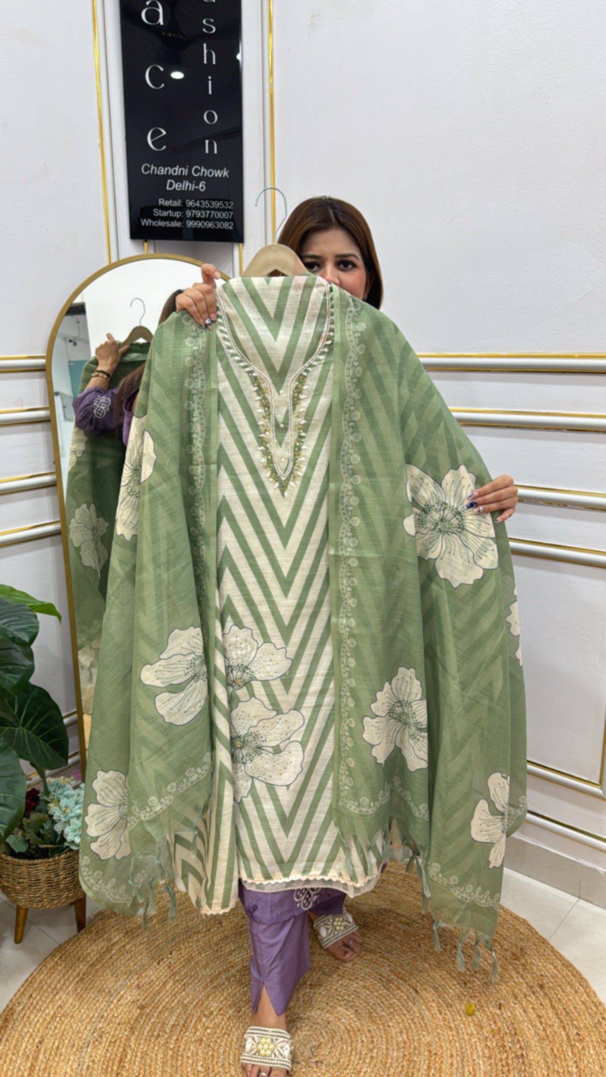 Woman holding a green unstitched linen shirt fabric with floral patterns and zigzag design