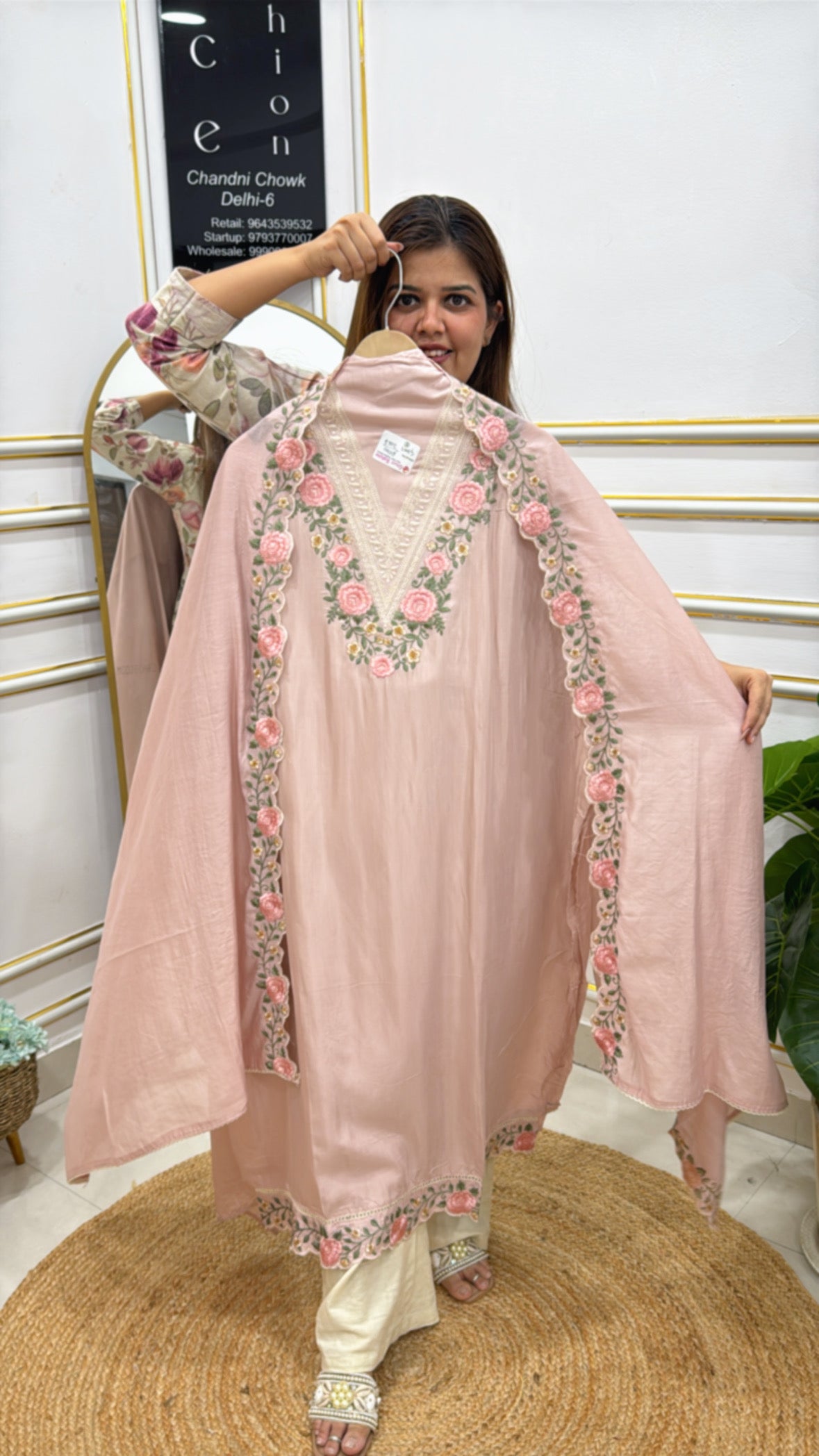 Elegant woman holding a modal cotton designer suit with floral embroidery and a v-neckline
