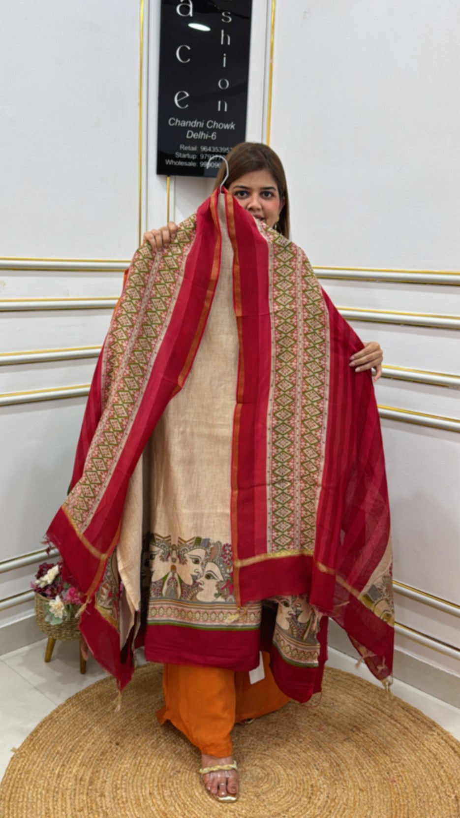 Woman showcasing a premium cotton silk suit with intricate floral designs and a vibrant red dupatta