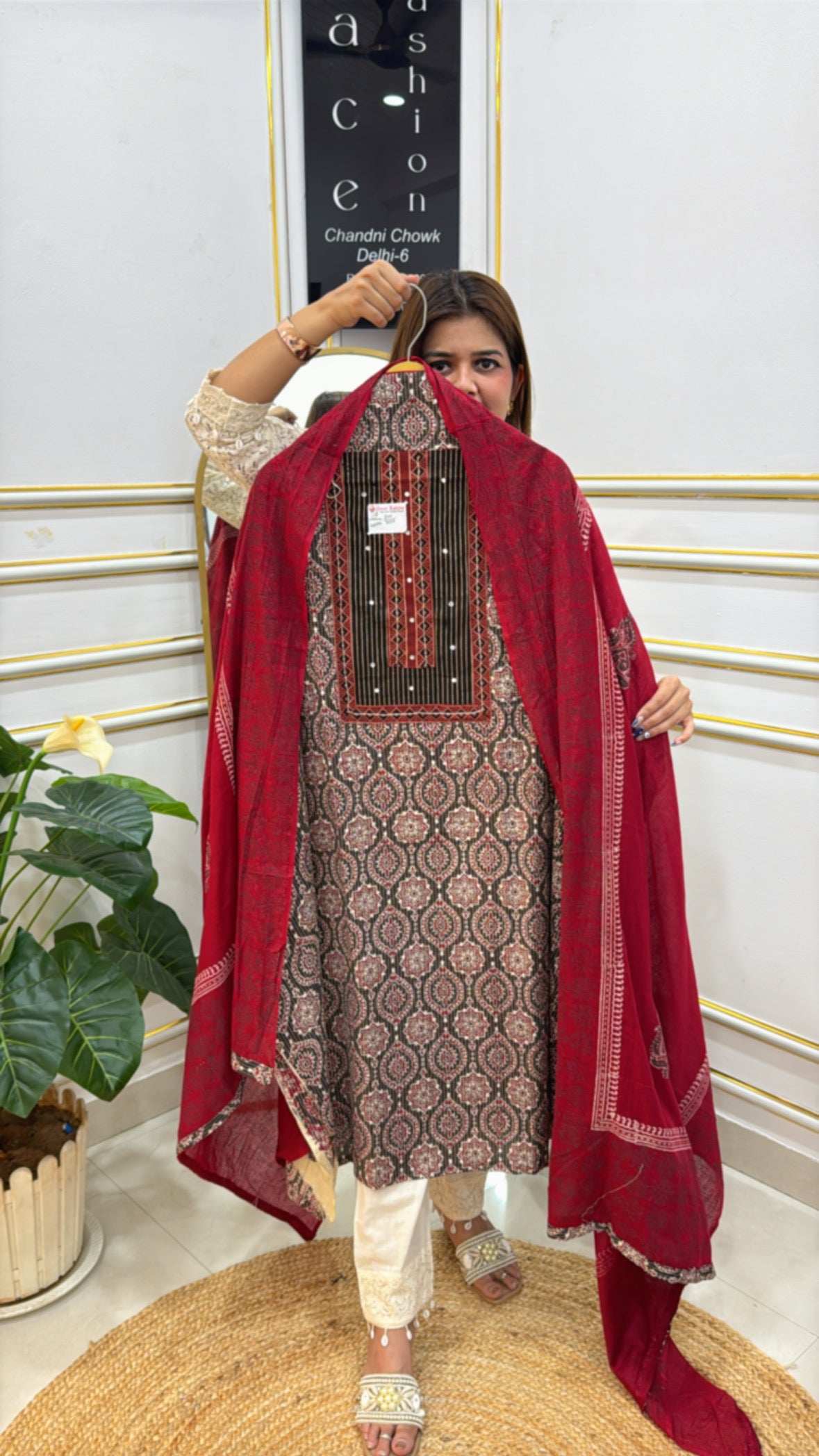 Model showcasing a premium cotton unstitched suit with intricate patterns and a contrasting red dupatta