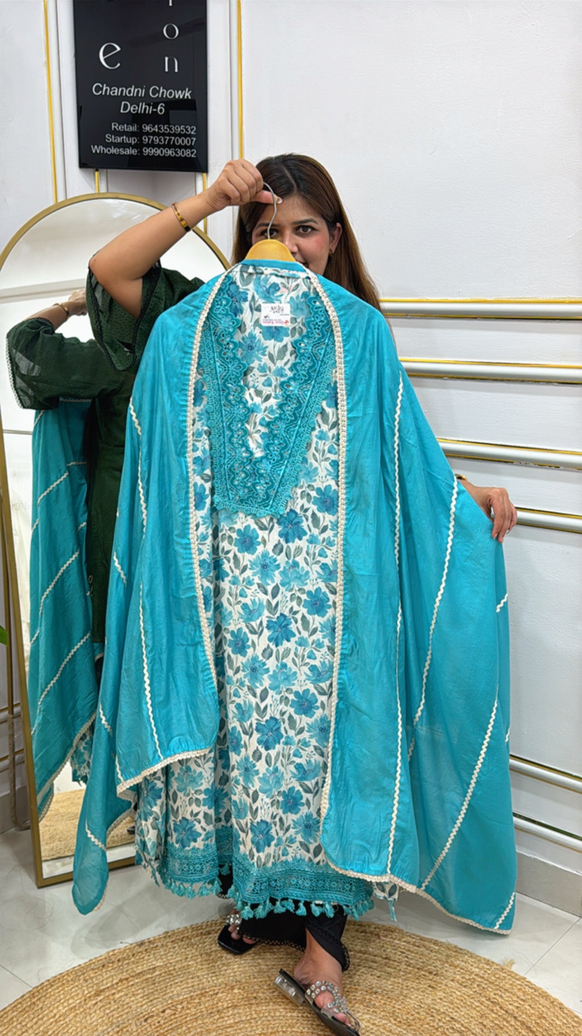 Woman showcasing a premium cotton unstitched suit in blue with floral patterns and elegant detailing