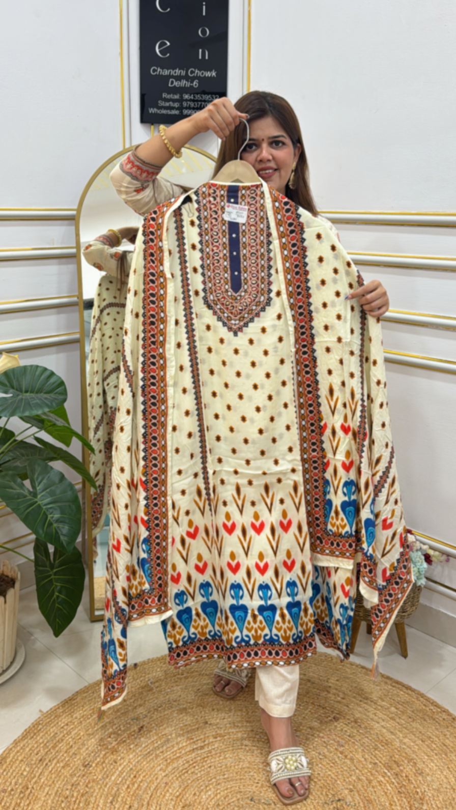 Woman holding a premium digital muslin suit with intricate patterns and colorful designs