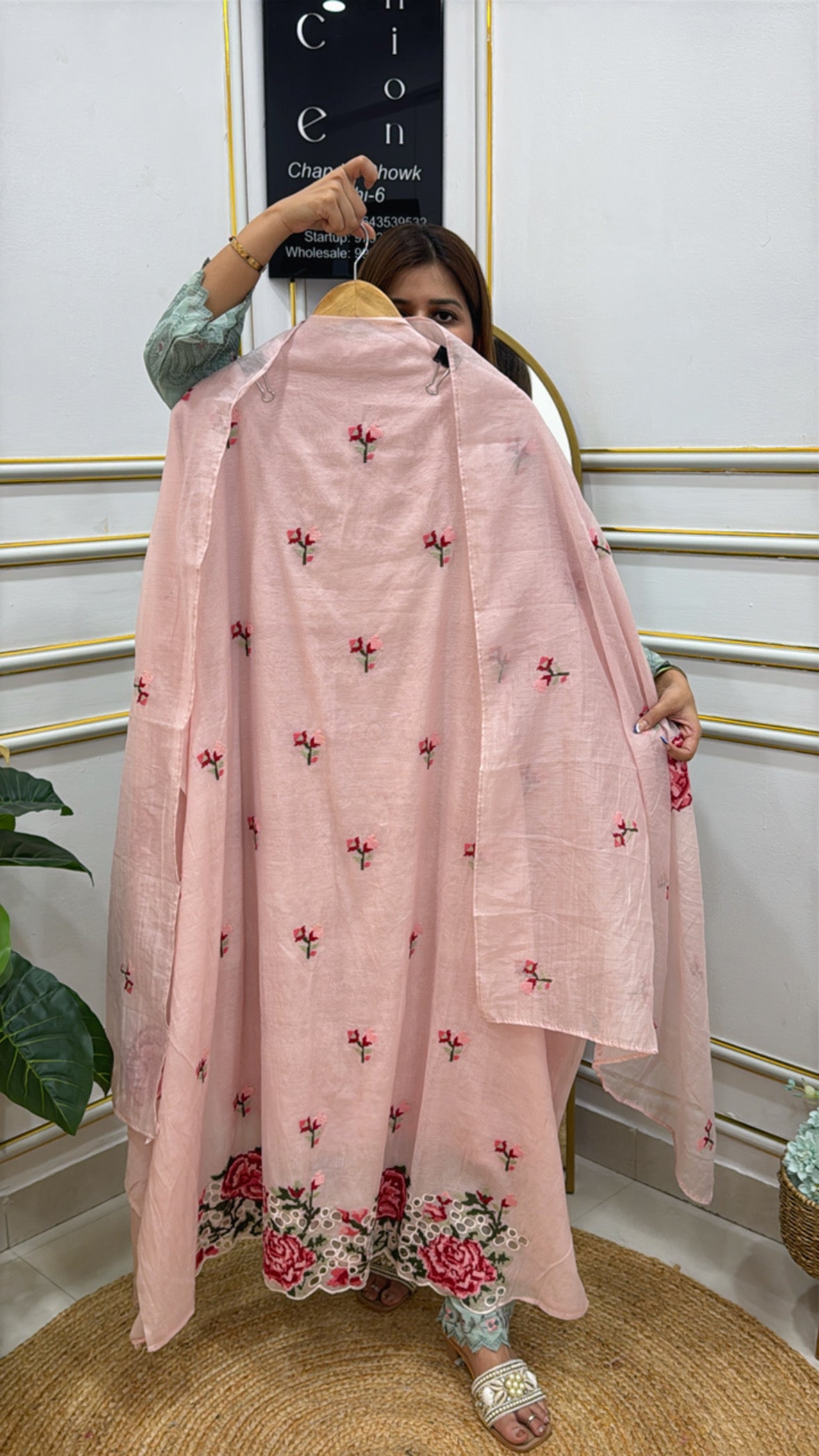 Model showcasing a premium embroidered fabric suit in pink with floral designs and matching dupatta