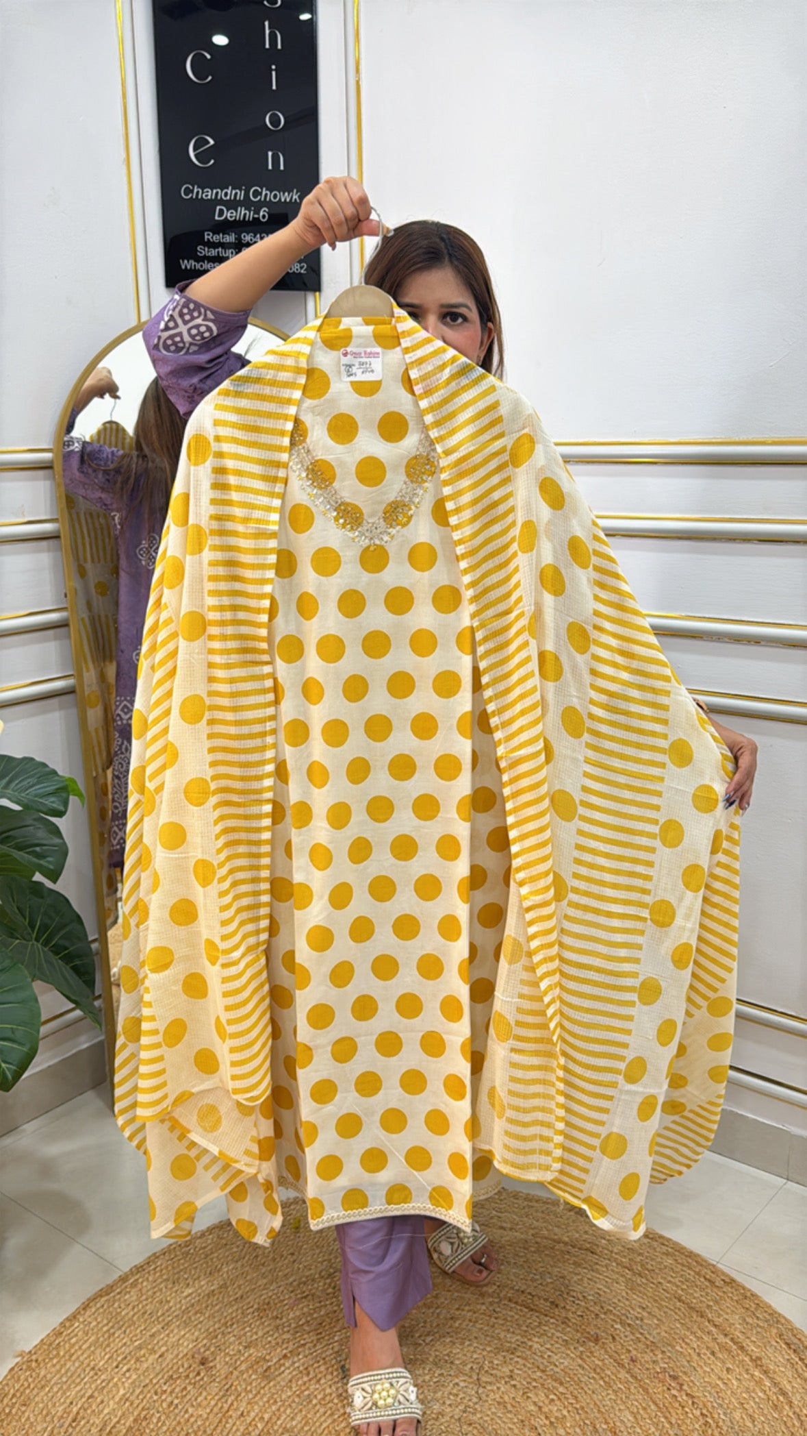 Woman holding a pure cotton polka dots suit in yellow and white with stylish design elements