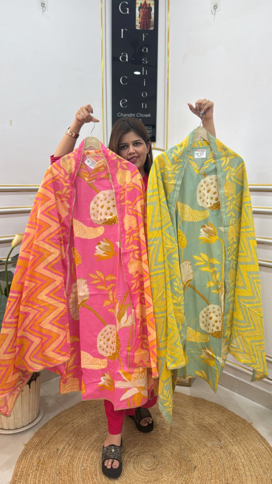 Vibrant unstitched ladies suits online in pink and green with floral patterns displayed by a woman